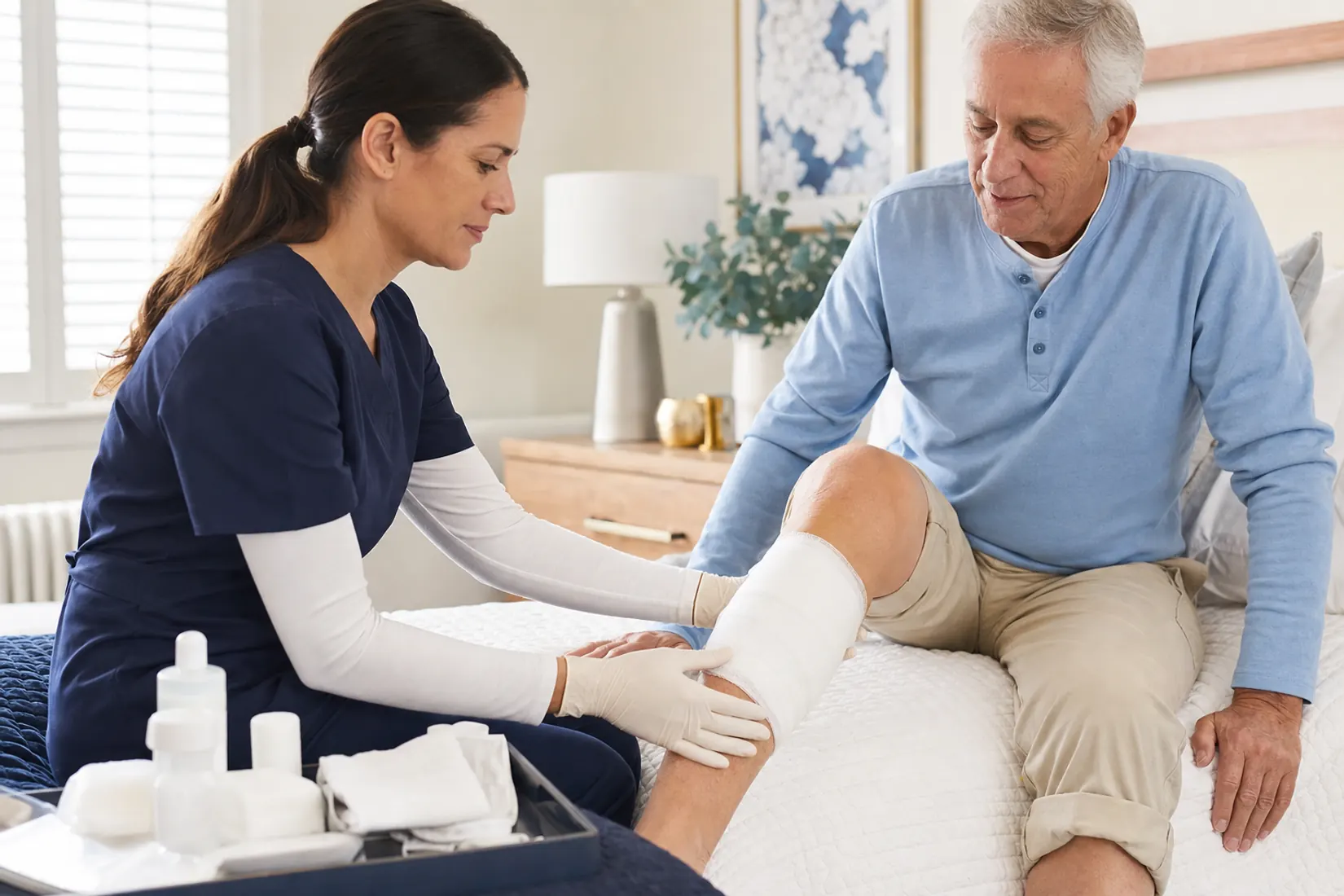 A clinician checking a patient's covered dressing during a home visit